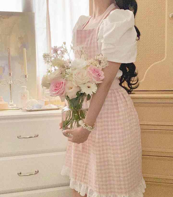 Walk-in closet in white and yellow tones, featuring a person wearing a pink apron holding a vase of flowers in a cozy setting