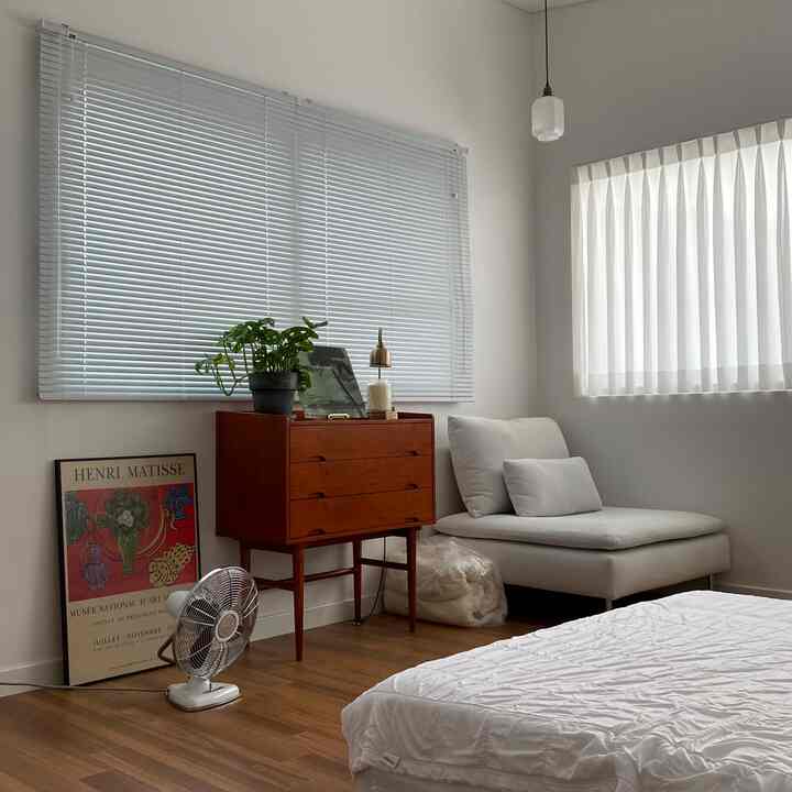 Bright white and wood tone bedroom featuring mid-century modern furniture and a clean layout in a natural modern style