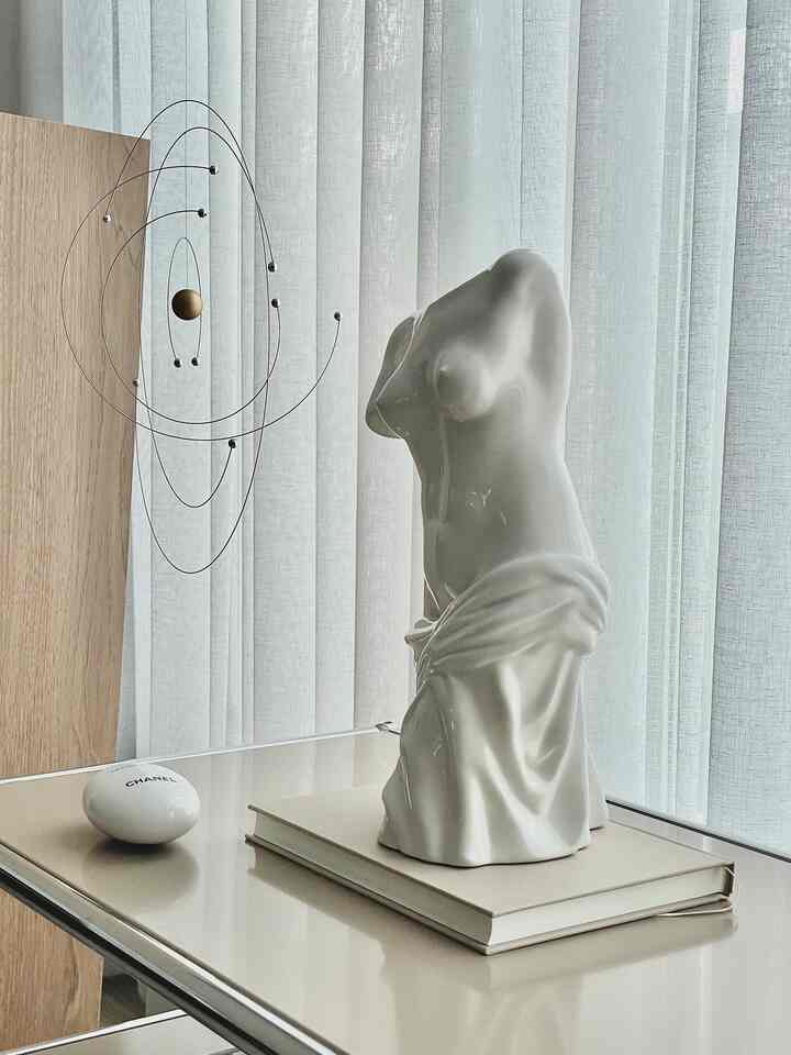 Beige and white toned living room featuring Venus plaster bust and wire mobile with a soft, gentle atmosphere