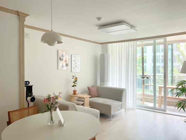 ホワイトとナチュラルウッドトーンの調和がとれた二人暮らしのリビング、ソファとキャットタワーが配置された雰囲気のある空間