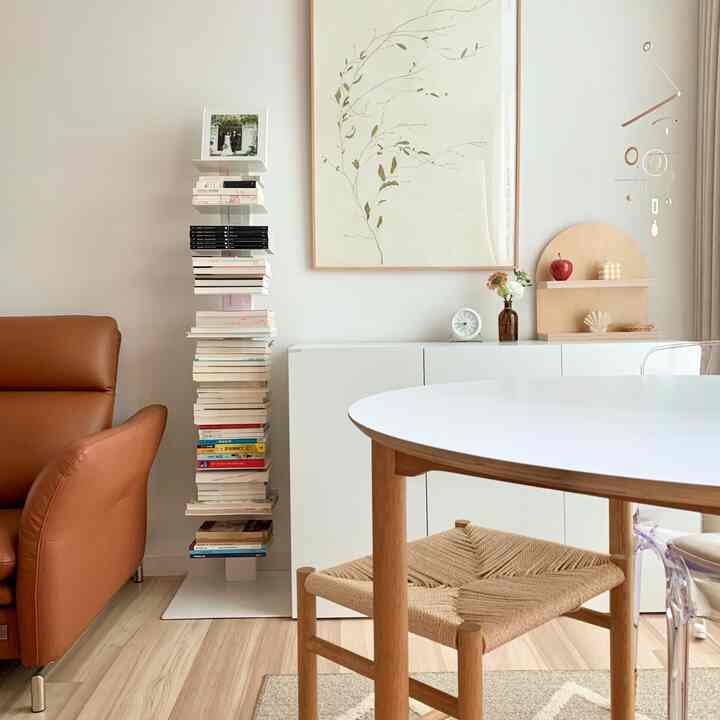 White-walled living room with wood tone furniture, featuring a bookshelf and sofa in a natural and tranquil setting