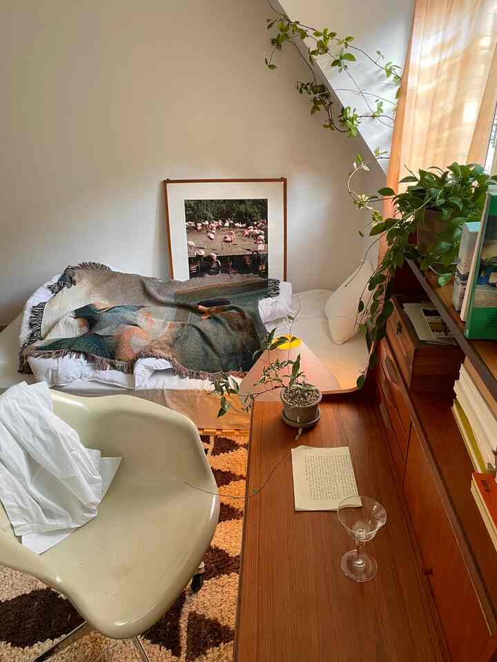 Ivory and wood tone bedroom featuring a desk, armchair, plants creating a cozy natural atmosphere