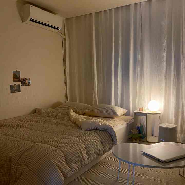 Beige and white toned bedroom featuring a large bed, curtains, and a bedside table lamp creating a warm atmosphere