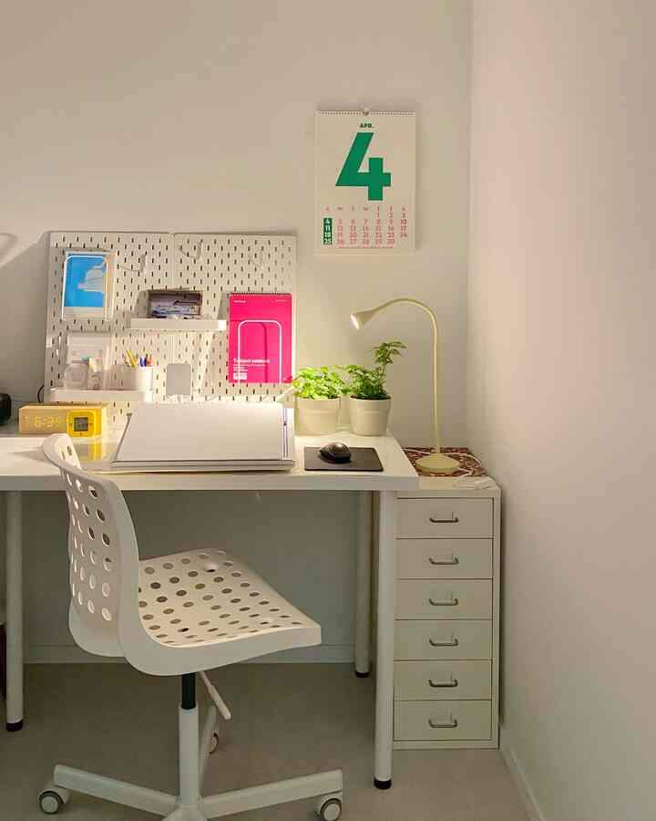 Clean white and beige toned home office featuring IKEA furniture, pegboard, plants, and a cozy workspace corner