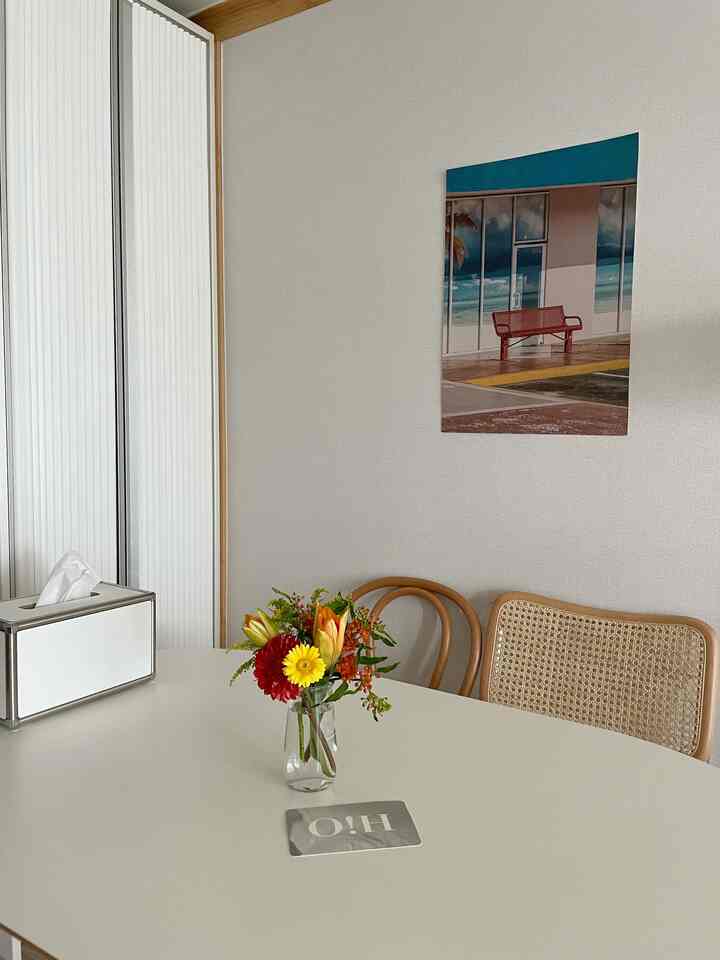 白と木目調が調和したダイニング、中央のテーブルに花瓶と花が置かれたナチュラルな雰囲気の空間