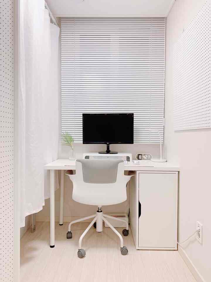 白とナチュラルカラーのトーンのホームオフィス、デスクとオフィスチェアが配置された清潔でシンプルな作業環境