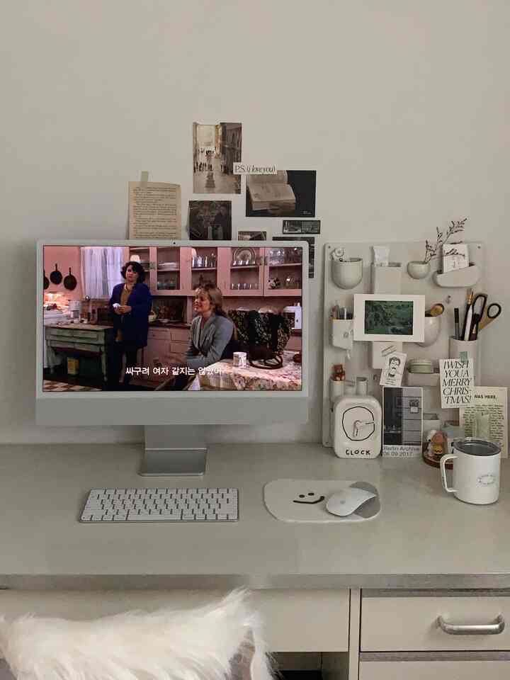 Soft white and gray toned home office featuring a clean desk with an iMac and wall-mounted storage board, creating a calm atmosphere