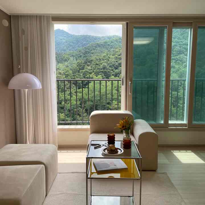 白とナチュラルカラーのリビング、ソファとサイドテーブルが配置された落ち着いた雰囲気のインテリア