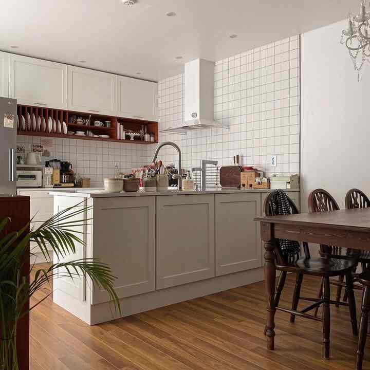 白い壁とタイルが調和するナチュラルな木目調のキッチン、木製のダイニングテーブルと椅子が配置された居心地の良いU字型の空間