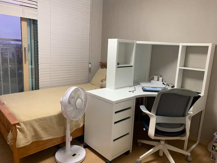Natural wood tone and white themed kids' room featuring corner desk and bed in a compact space