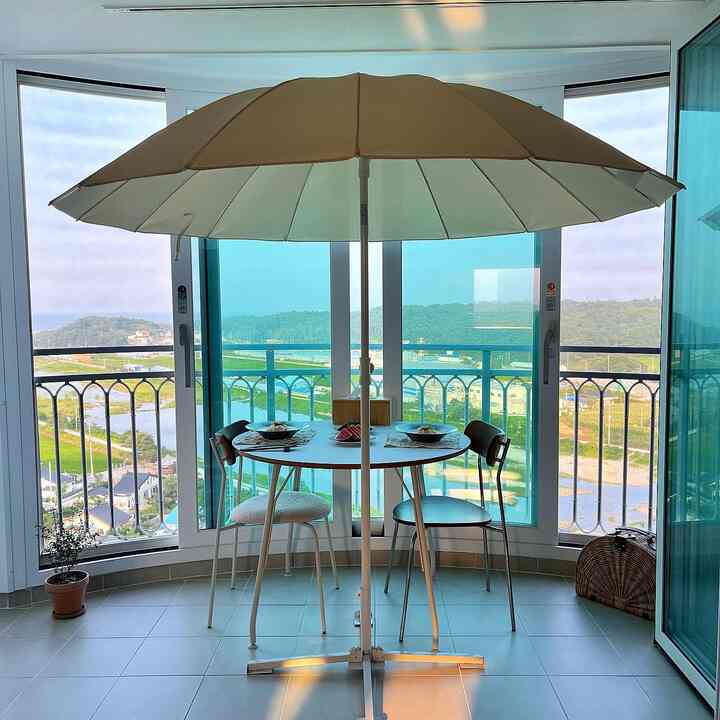 White and navy toned veranda space featuring a parasol and dining set creating a cozy summer evening atmosphere