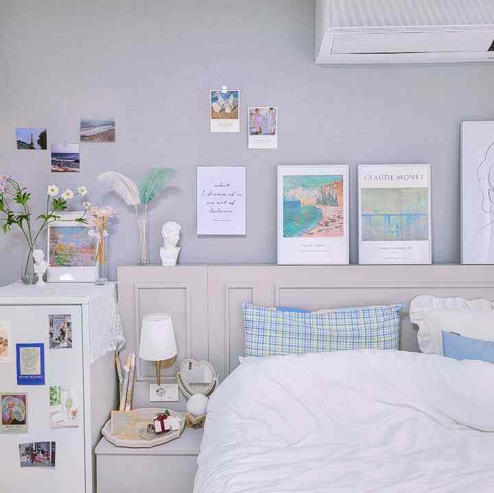Soft white and blue toned bedroom and study featuring framed art and vases in a cozy setting