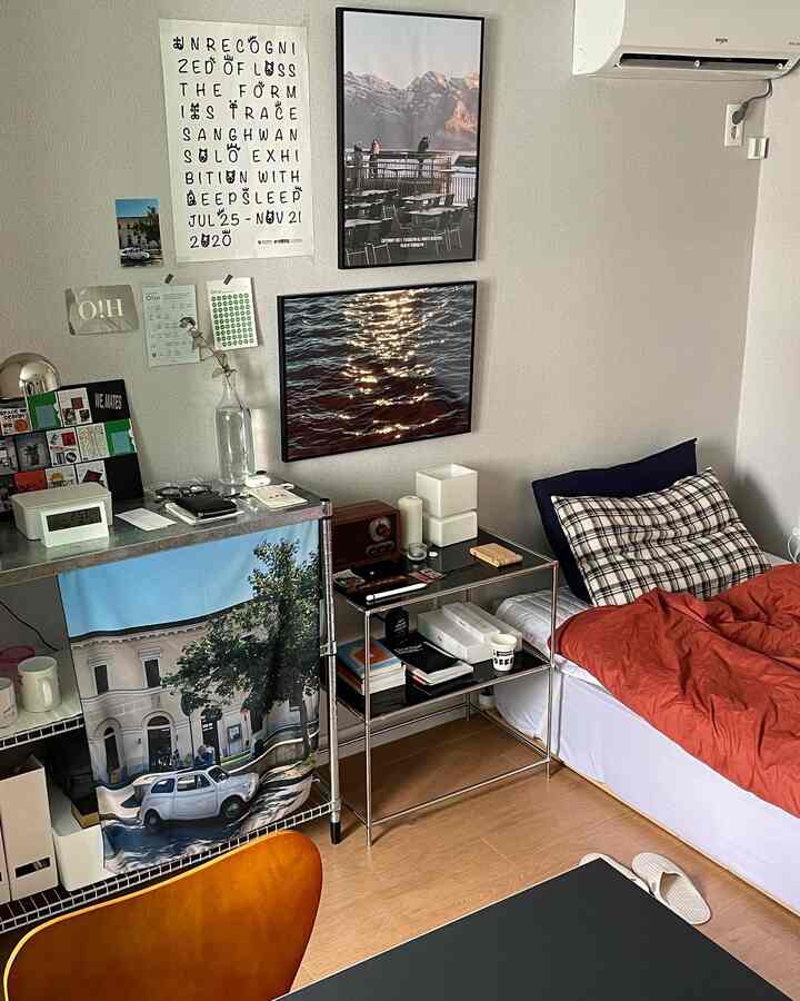 Natural color and wood-toned studio bedroom featuring a tidy desk, framed artworks, and a cozy gallery-like wall decor
