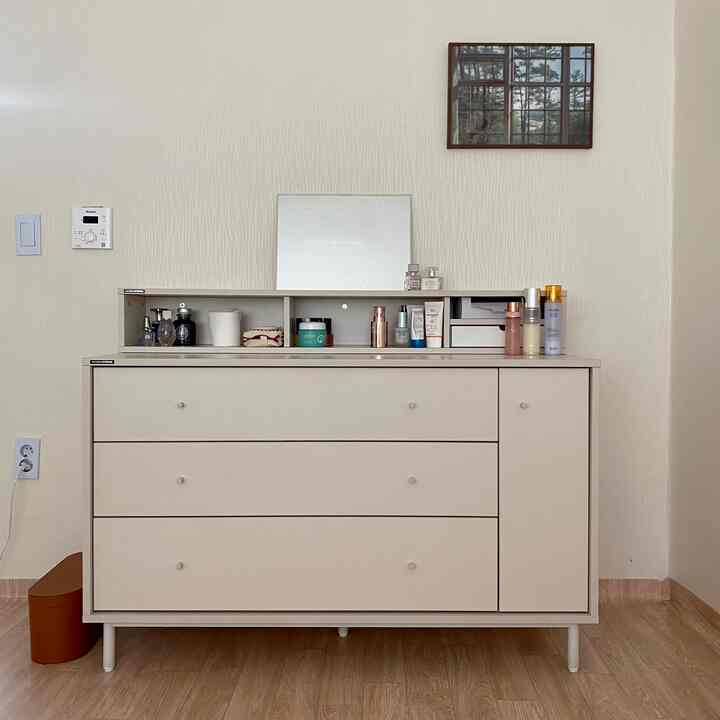 Beige-tone room with a large vanity dresser centered against the wall and a mirror on top, creating a neat atmosphere