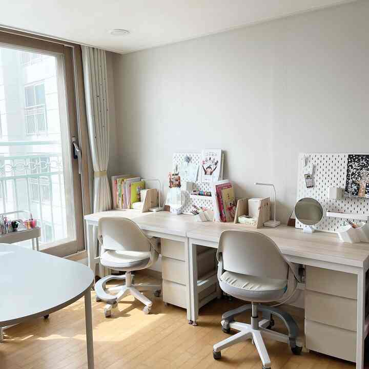 明るいナチュラルカラーの二人用子供の勉強部屋、二つの机と椅子、ペグボードが配置された整った空間