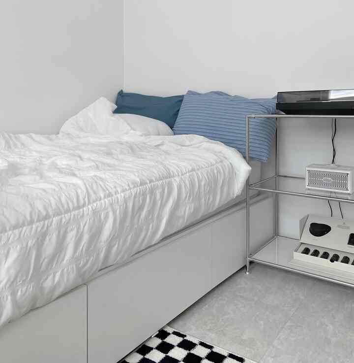 白と青のトーンのモダンな寝室、収納ベッドとシンプルな金属製の棚が配置された雰囲気のあるインテリア