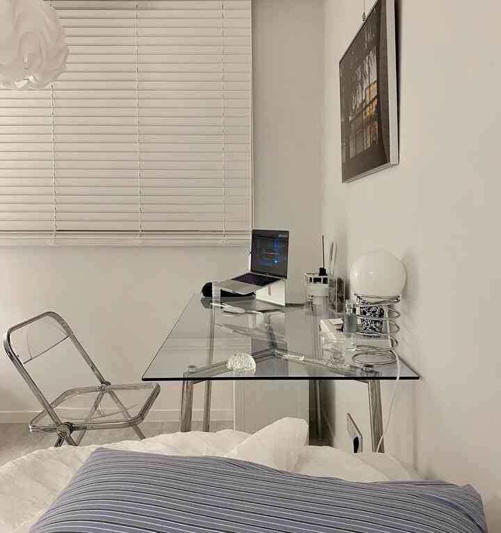 White and transparent-themed bedroom home office featuring glass desk and clear chair with modern simplicity