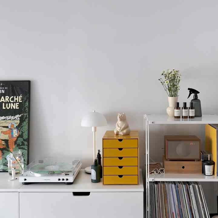 白を基調とした背景に黄色の収納ボックスが配されたミニマルなリビング空間、オーディオテクニカのターンテーブルと棚を配置