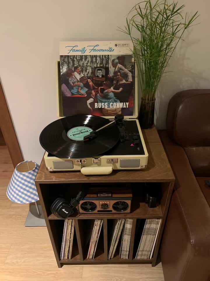 Vintage music listening space in wood and brown tones featuring an analog turntable, LP record, and a green plant, creating a cozy ambiance