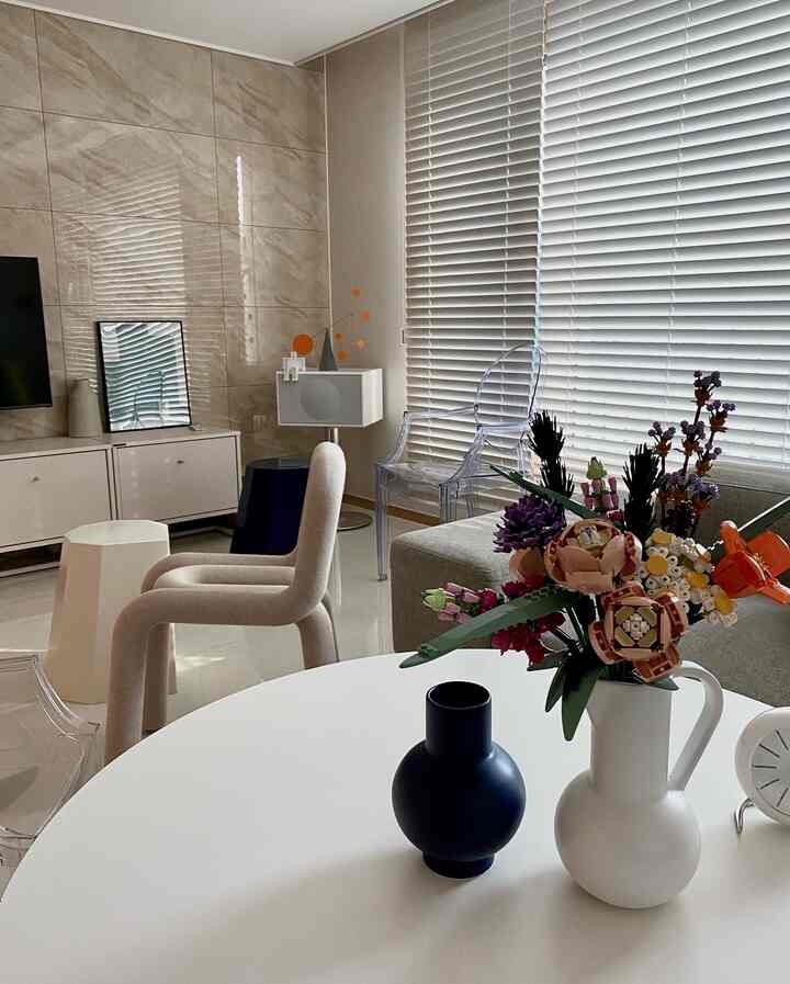 White and wood tone living room featuring sofa, blinds, and a vase with a Lego bouquet in a simple, harmonious interior