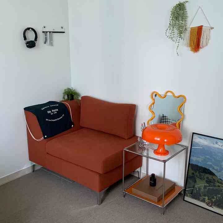 レンガ色のソファとオレンジ色の照明があるシンプルでナチュラルな一人暮らしのリビングスペース