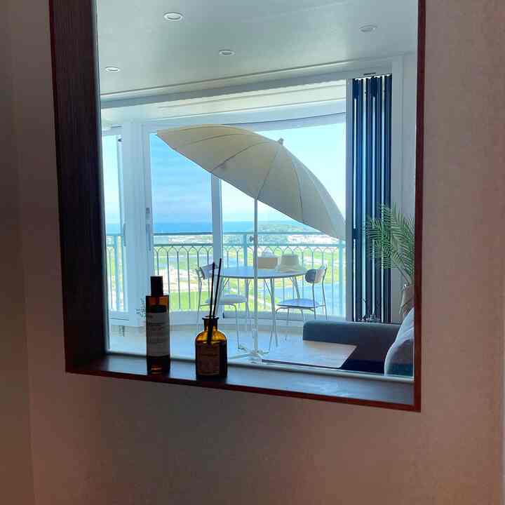White and navy tone entrance view overlooking living room and veranda with large glass window and room divider creating openness and natural light