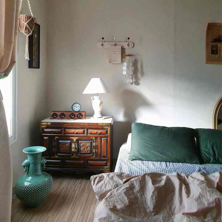 A natural beige and wood tone bedroom featuring vintage nightstand, lighting, and wall art creating a cozy atmosphere