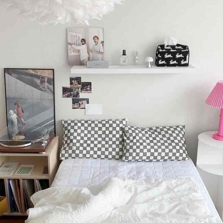 White-toned bedroom featuring checkerboard pillows and neat furniture in a modern setting