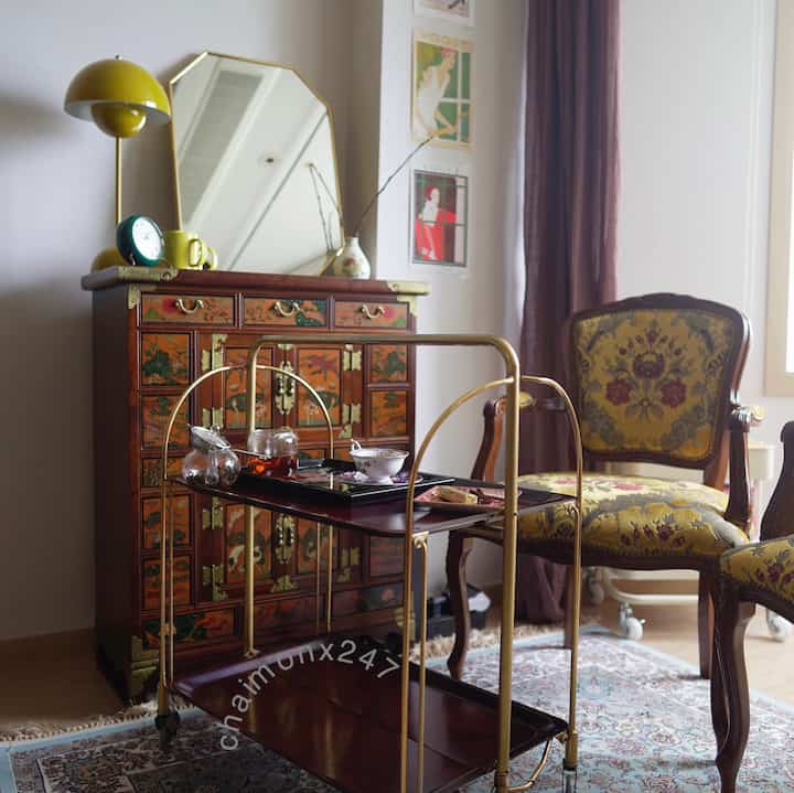 Brown and gold toned living room featuring antique cabinet, vintage armchair, and gold metal trolley for cozy atmosphere