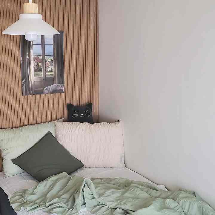 Natural colors and wood tones in a studio bedroom featuring seersucker summer bedding and a pendant light for a cozy atmosphere