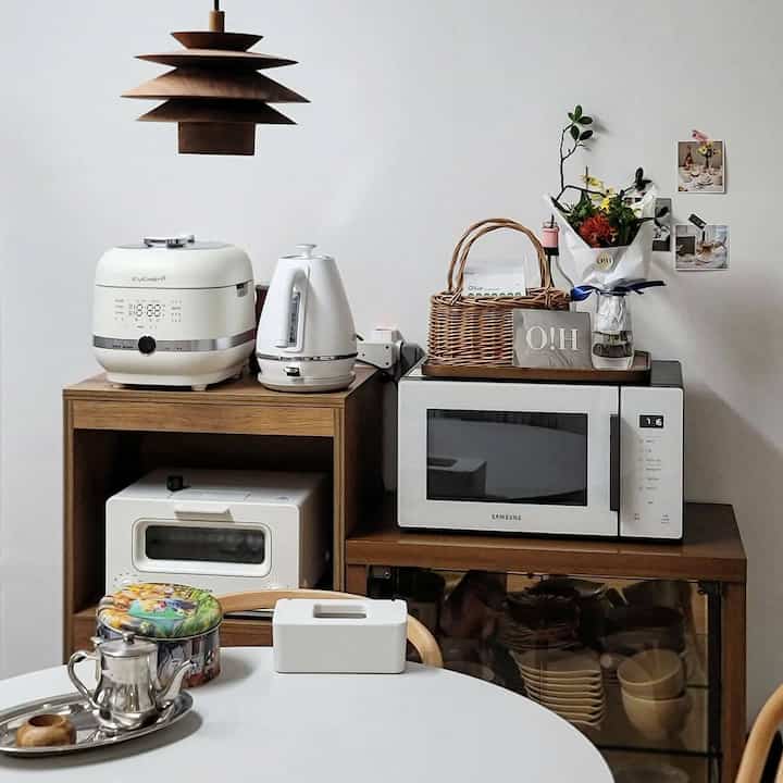 A natural dining room featuring white and wood tones with neatly arranged electronics and a wooden pendant light