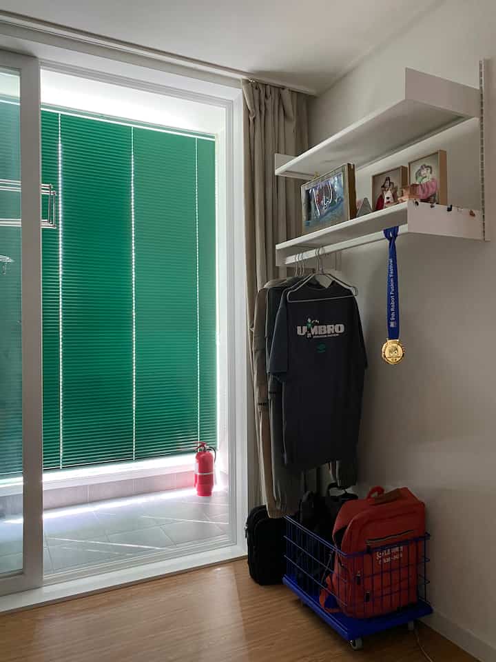 Small kids' room corner with green blinds, hanging clothes, and a storage basket, featuring a modern and compact setup