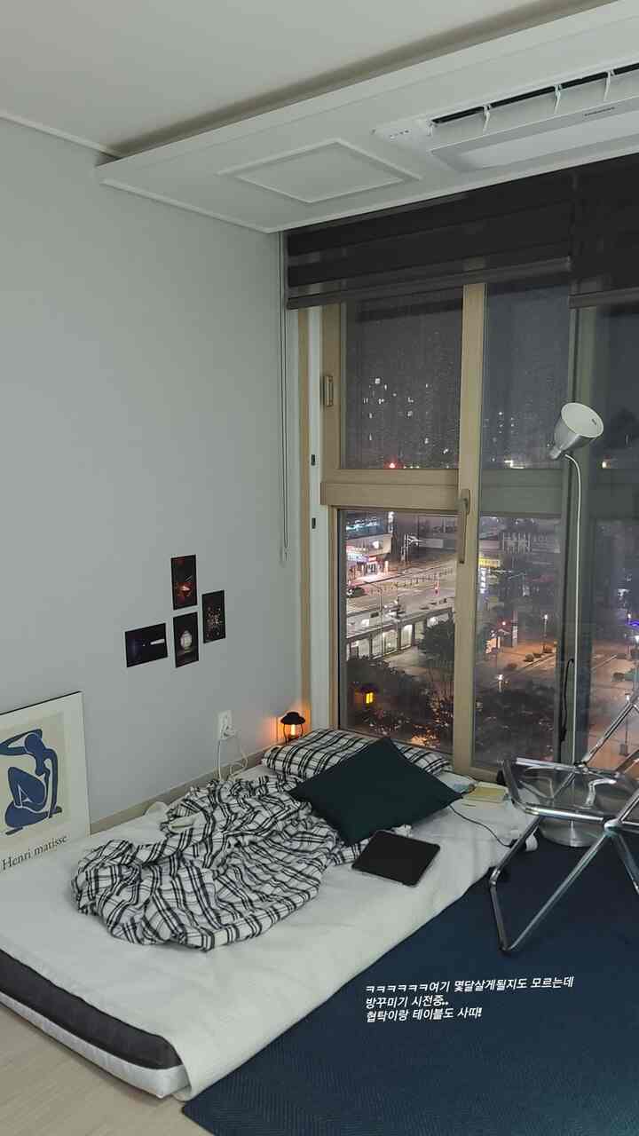 ネイビートーンのワンルーム寝室、透明な椅子とフロアランプが配置された居心地の良い一人暮らしの空間