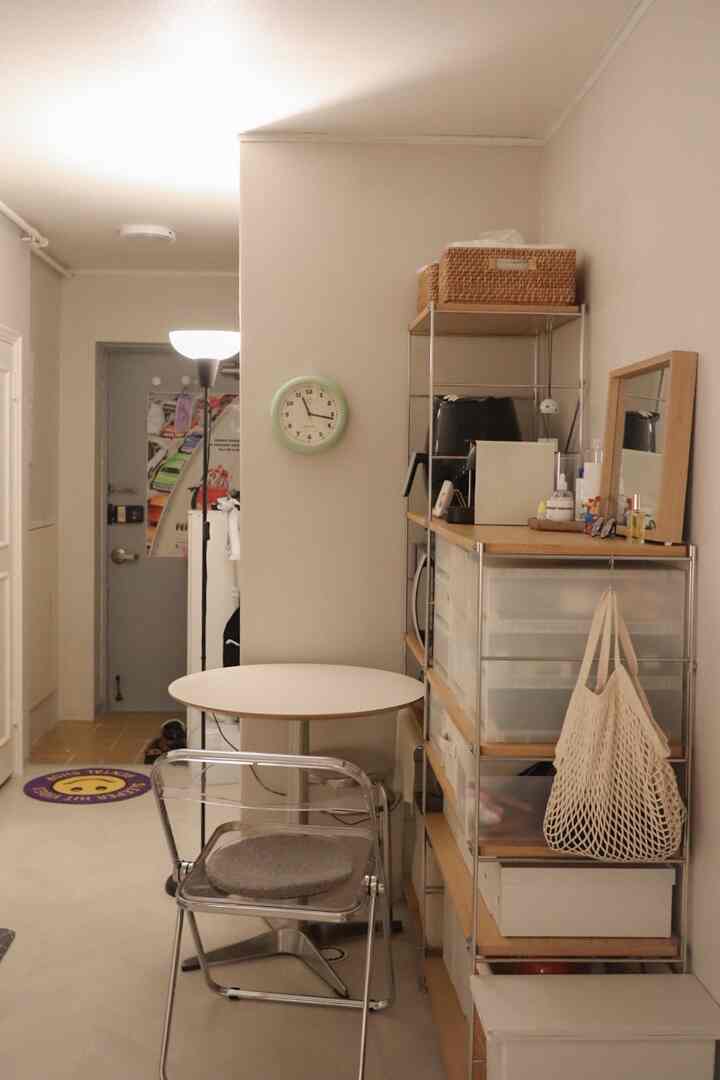 白と木目調の調和が取れた狭いキッチン空間、無印良品棚とフロアランプが配置された雰囲気のある小さな家