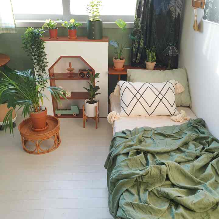 Natural tone small bedroom featuring a single bed and various plants with a cozy atmosphere