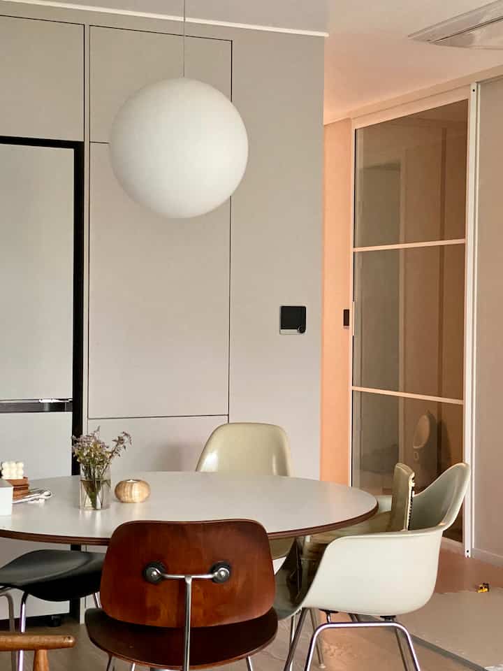 Natural beige and white tone round dining space featuring vintage and modern chairs with warm ambiance