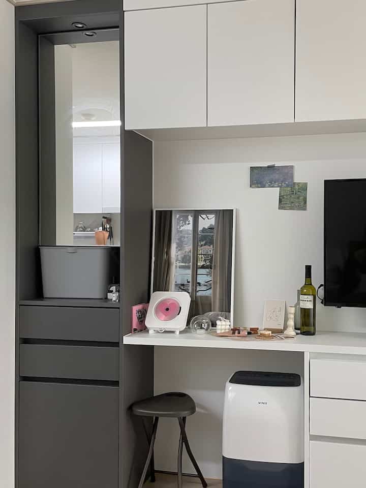 白と黒のトーンのワンルーム、化粧台と収納が配置された印象的で実用的なインテリア