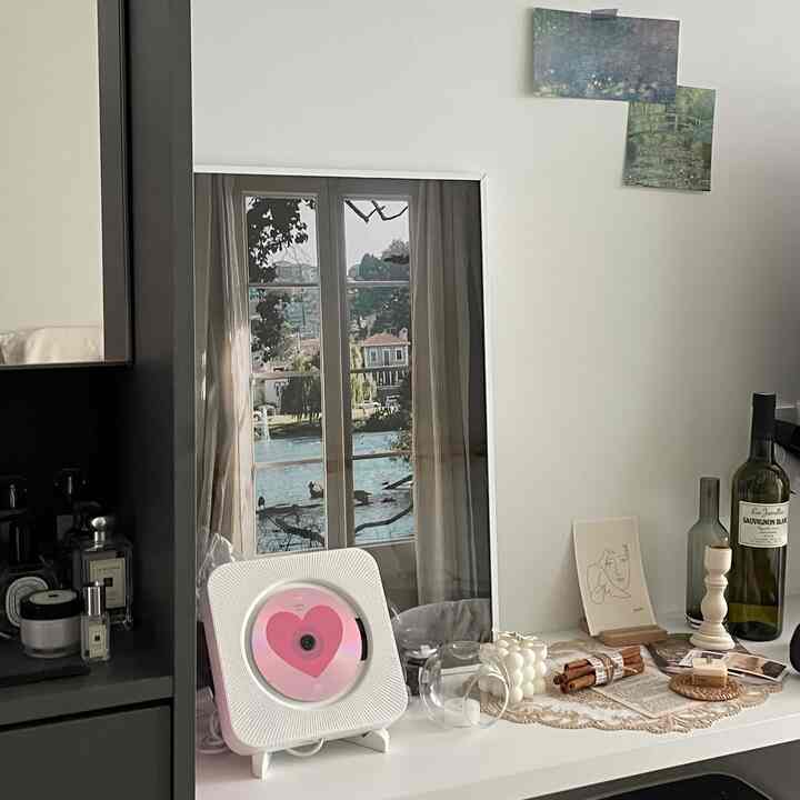 A white and brown toned accessory space beside a vanity, featuring a poster, candle, and wine bottle with cozy atmosphere