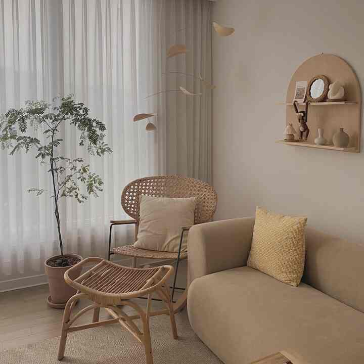 ベージュとナチュラルカラーのリビング、ラタンのスツールとアームチェア、快適なソファが調和した雰囲気のあるインテリア