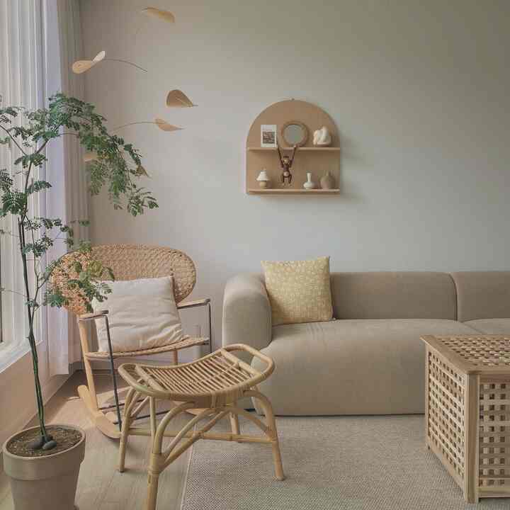 Beige and wood-tone living room featuring rattan chair, stool, and sofa with a natural and cozy atmosphere