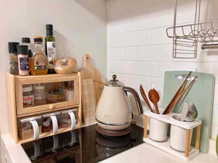Natural-toned kitchen featuring wooden cutting boards and utensils along with an electric kettle in a clean setting