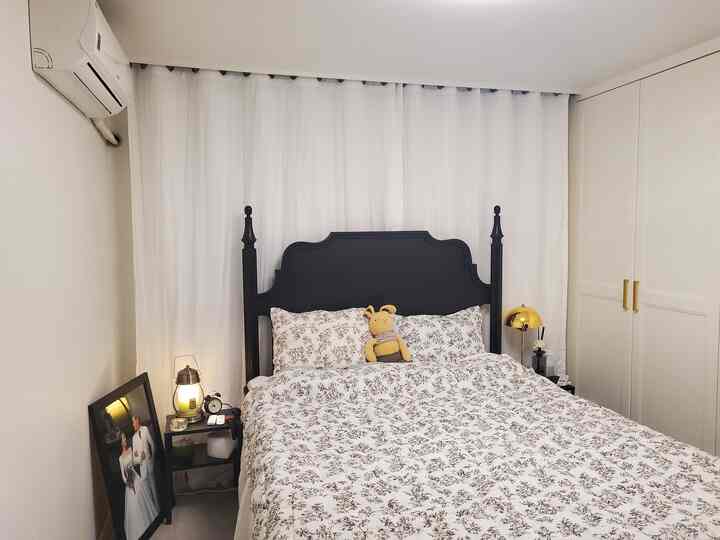 White and black toned bedroom featuring floral bedding, nightstand, and an inviting cozy atmosphere