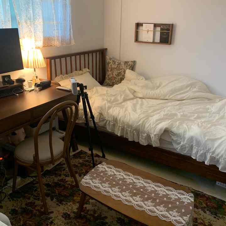 Ivory frilled duvet and cushions on bed in vintage-style bedroom featuring wooden bed frame and desk