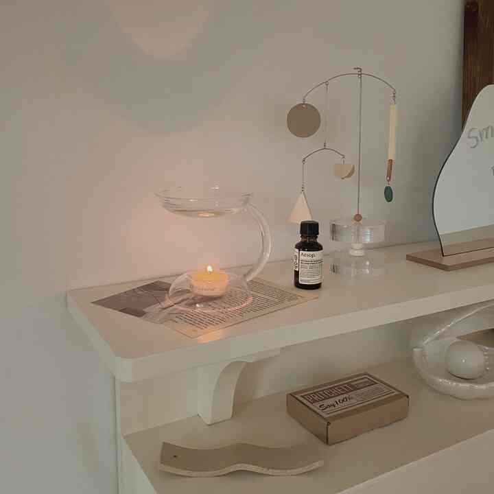 Natural color-toned wall shelf displaying an oil burner, aroma oil, and mobile, creating a cozy and calming atmosphere