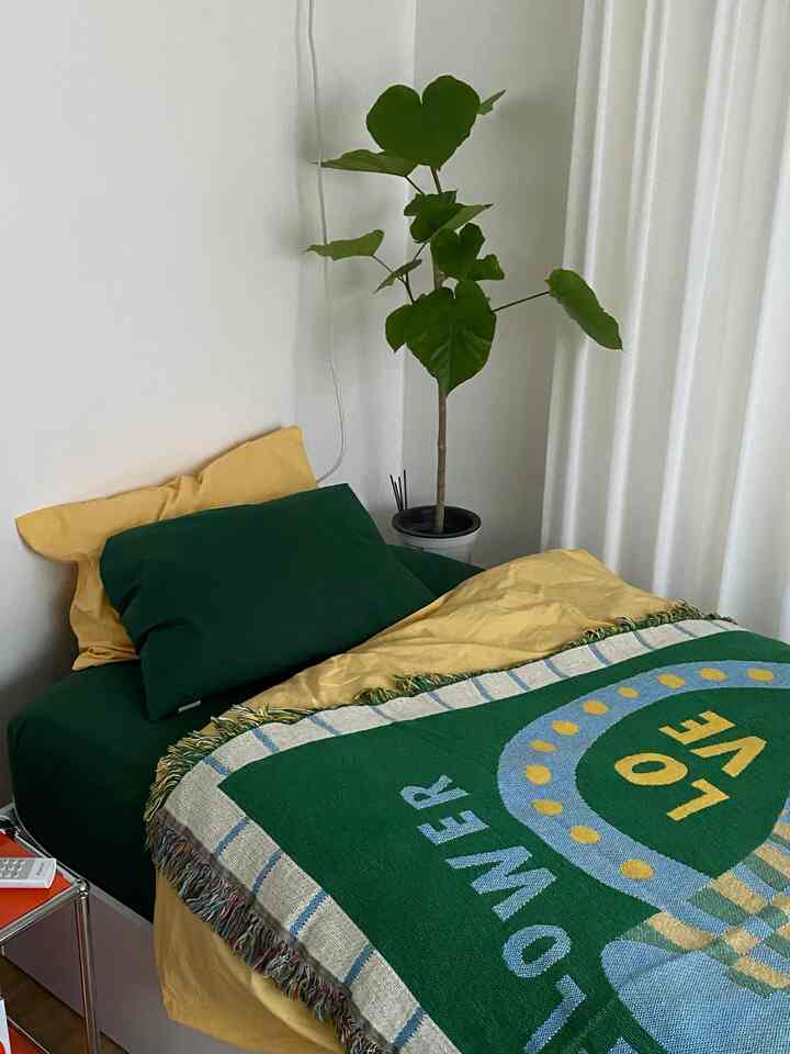 Yellow and green toned bedroom featuring bed, pillows, and throw blanket with a natural atmosphere
