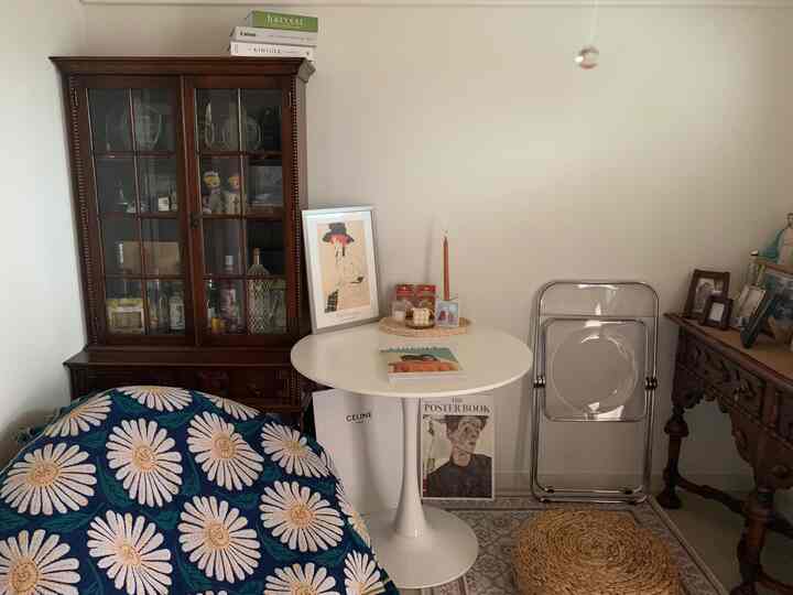 Cozy natural toned loft home cafe featuring dark wood cabinet, white round table, and transparent folding chair with relaxed atmosphere