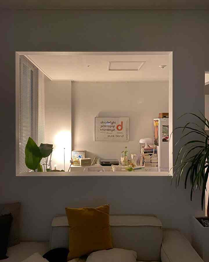 白を基調に黄色のアクセントがあるリビング、ソファやデスク、フロアランプが配置された落ち着いた空間