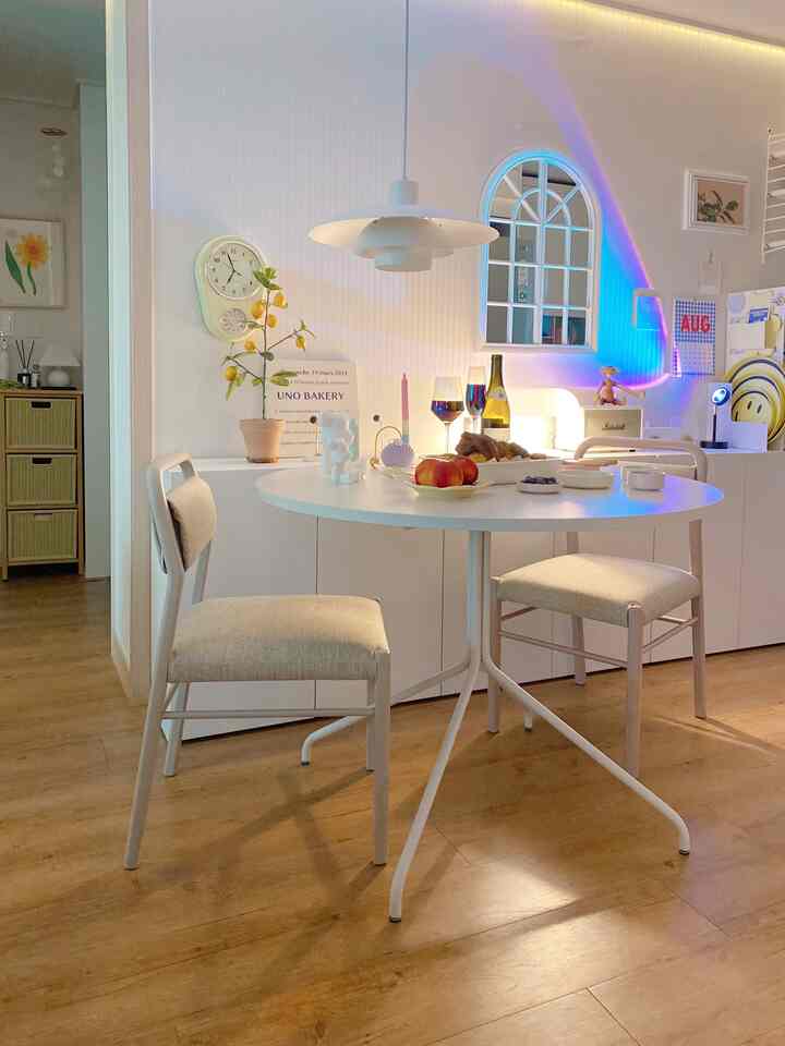 Simple kitchen dining room in white and wood tones featuring a round dining table and pendant light creating a harmonious atmosphere