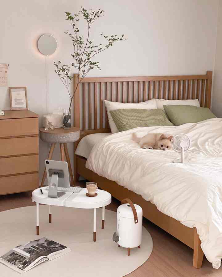 Natural wood tone bedroom featuring a wooden bed frame and nightstand, with a small dog resting on the bed