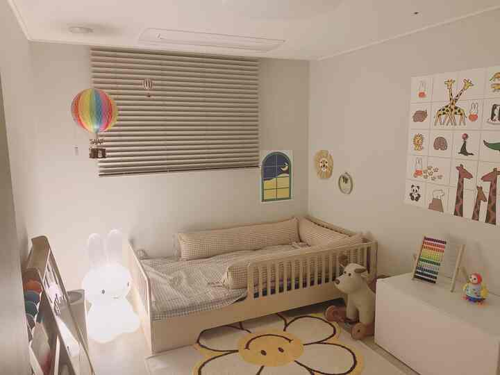 Warm beige and ivory toned baby room featuring a crib, floral rug, wall decor, and a colorful hot air balloon mobile creating a cozy atmosphere